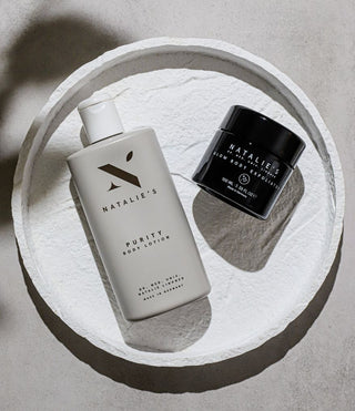 Purity body lotion and glow body exfoliator lying on a stone plate