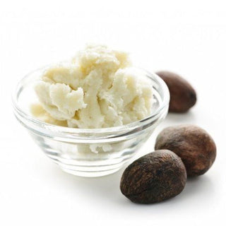 Shea butter in a glas jar with three shea nuts on the side