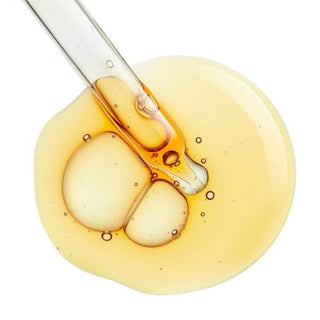 Yellow drop of Vitamin A coming out of a pipette