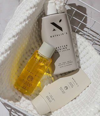 Our Better Aging body lotion, body oil and hand cream lying on a towl in a basket